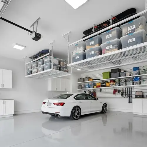 Overhead ceiling racks storing seasonal items above a garage gym to free up floor space.
